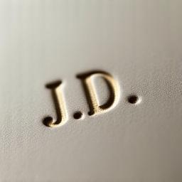 Close-up of a ceramic surface with a subtly engraved monogram, showcasing personalized detail on a pottery piece.